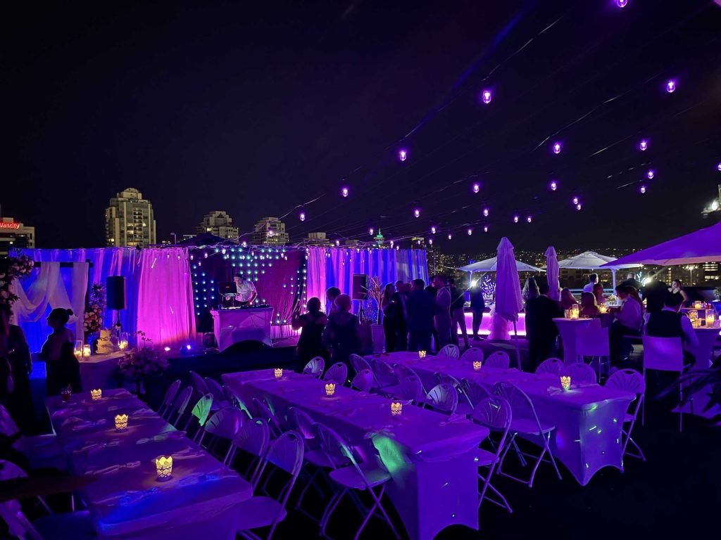 Rooftop party with tables and lights.